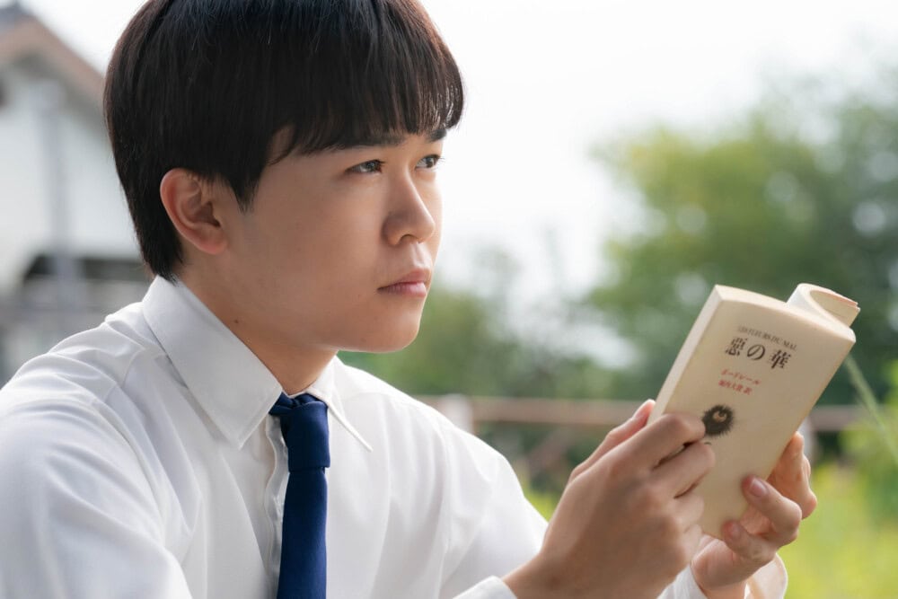 鈴木福飾演的春日高男手持波特萊爾《惡之華》